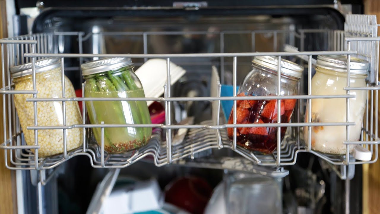 Mason jars being loaded into a dishwasher for safe cleaning